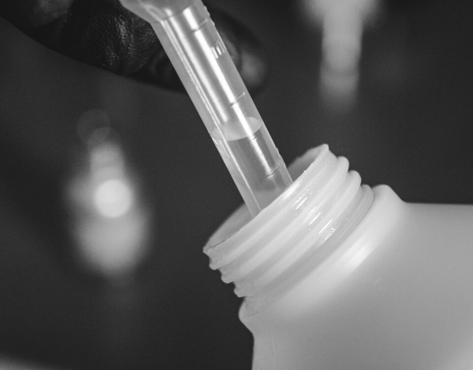 Devo usar produtos químicos para desentupir canos? a person is holding a plastic bottle with a straw in it