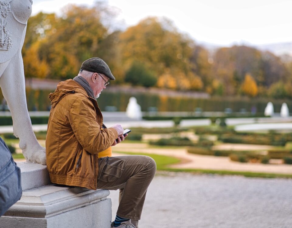 Empréstimo consignado vale a pena para aposentados? a man sitting on a bench looking at his phone