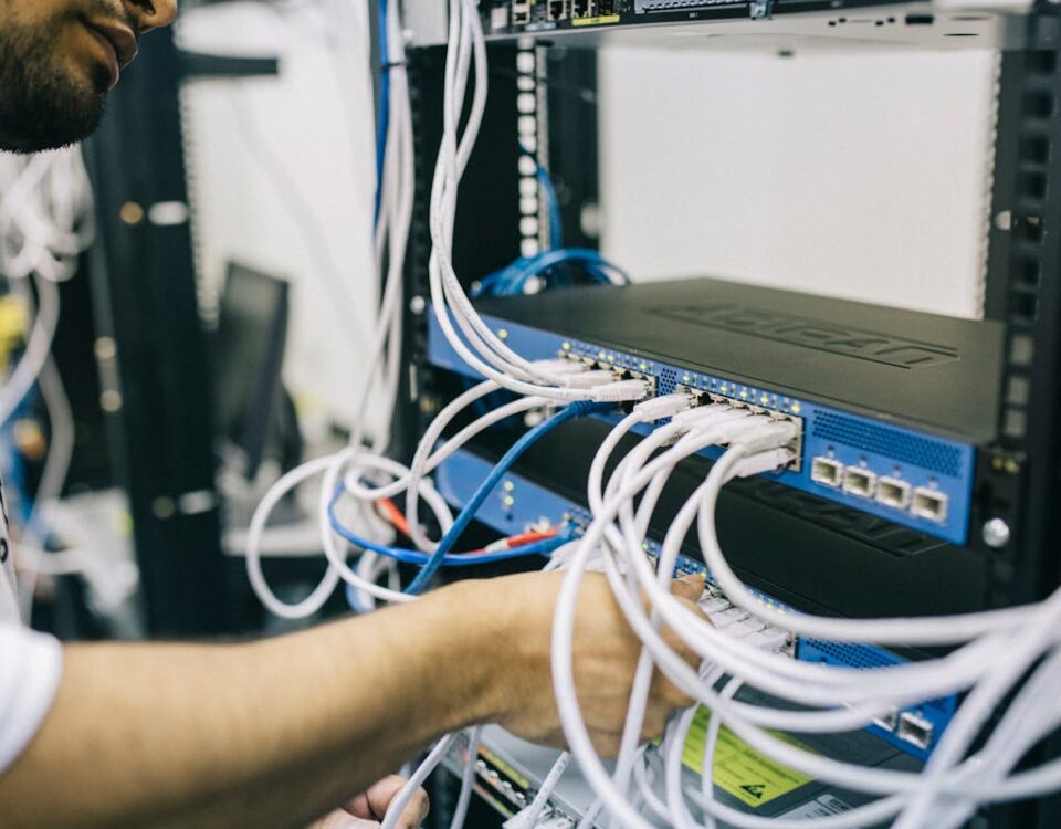 Por que link dedicado é útil mesmo em empresas menores? An IT professional configuring network cables in a server rack, focusing on Ethernet connections.