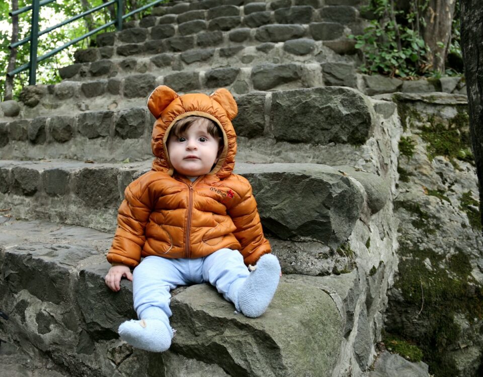 Como escolher o melhor tecido para roupas infantis? a small child sitting on some steps