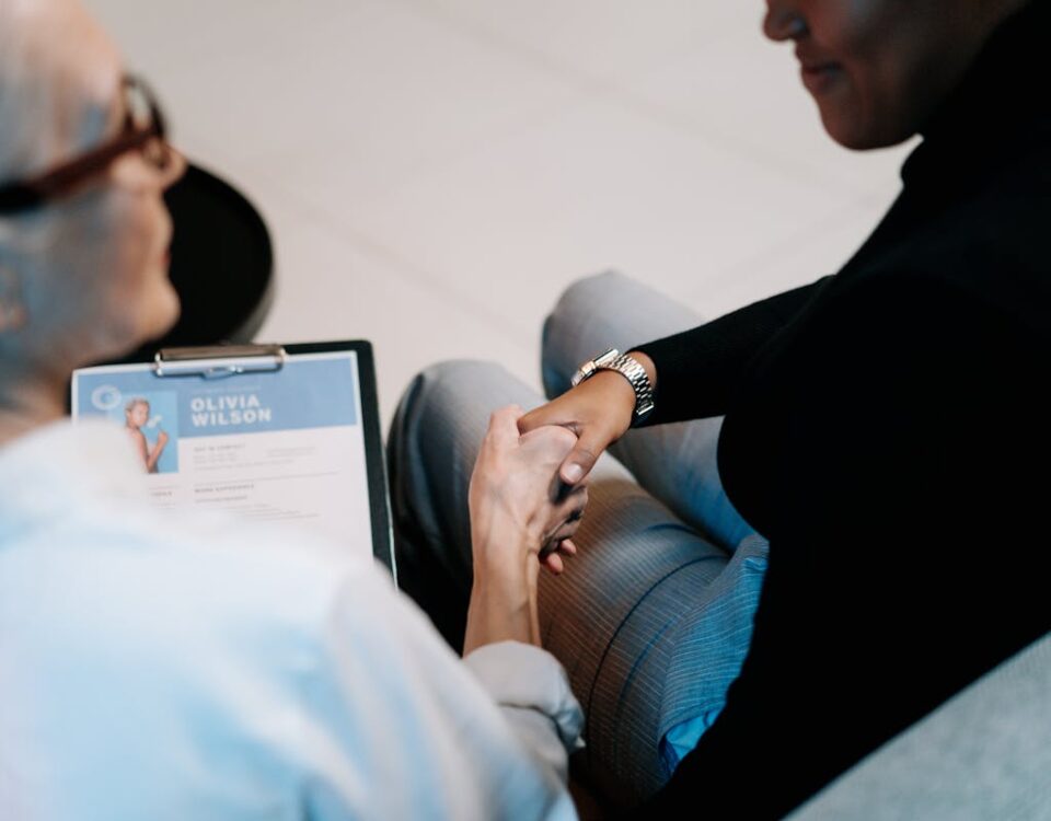 O que faz um bom currículo se destacar hoje? Two professional women having a handshake in an office setting, focusing on recruitment and connection.