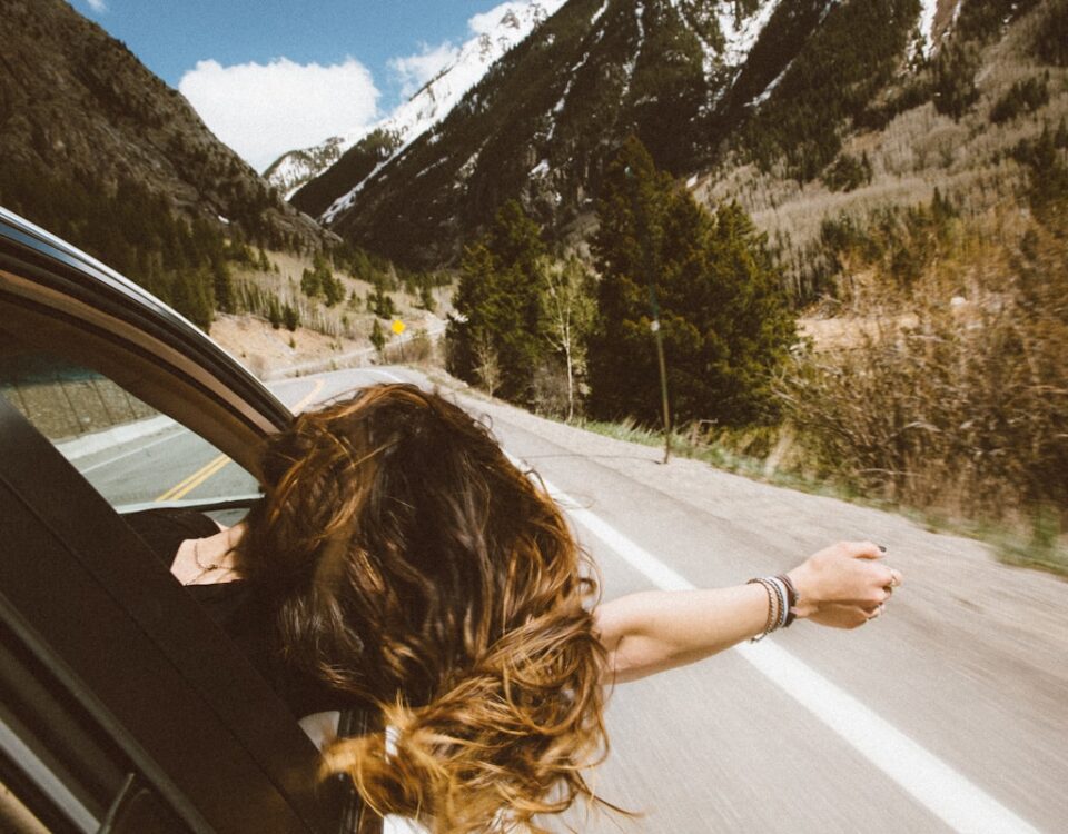 Seguro viagem: Qual o tipo certo para cada perfil? woman riding on vehicle putting her head and right arm outside the window while travelling the road