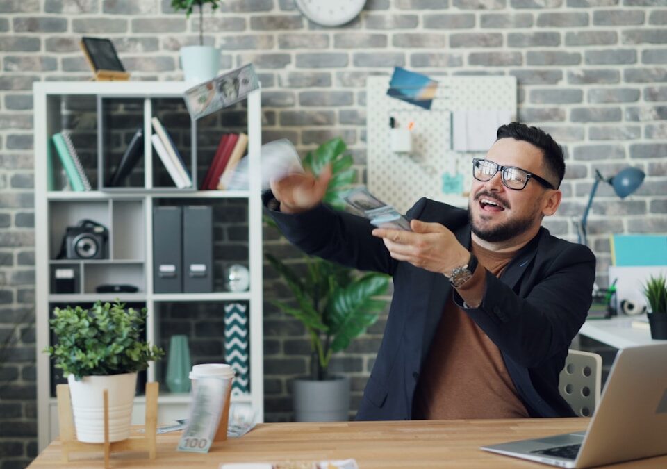 Como sua personalidade influencia seu dinheiro? a man sitting at a desk holding a remote control