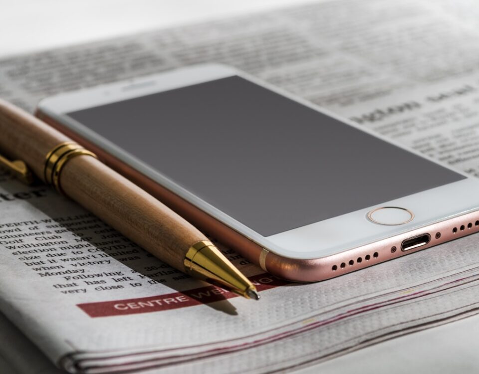 O que faz uma notícia viralizar na internet a cell phone sitting on top of a newspaper next to a pen
