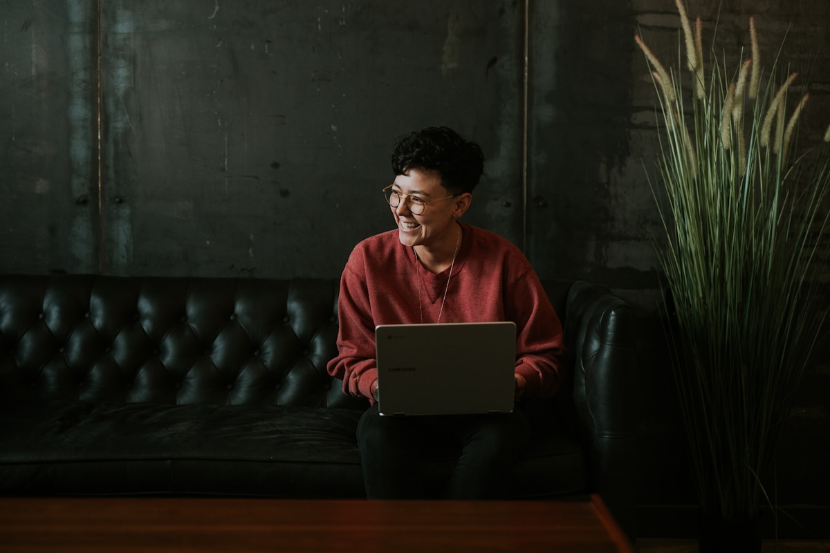 Qual o curso ideal para quem quer mudar de carreira? smiling man using laptop computer while sitting on black leather sofa