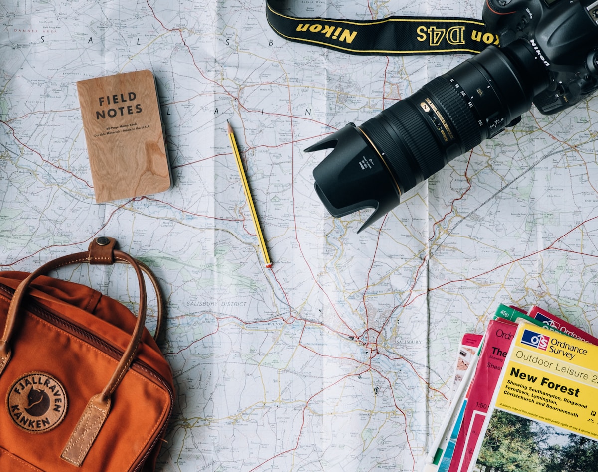 Seguro viagem: Qual o tipo certo para cada perfil? flat lay photography of camera, book, and bag
