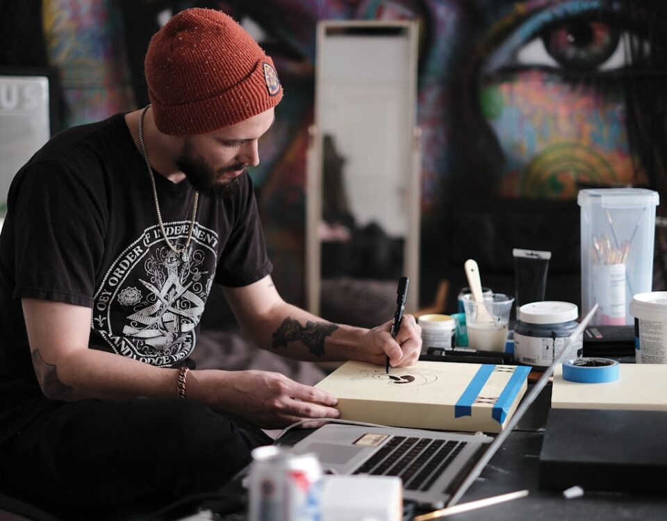Como o marketing digital pode impulsionar artistas? a person with a red hat writing on a laptop