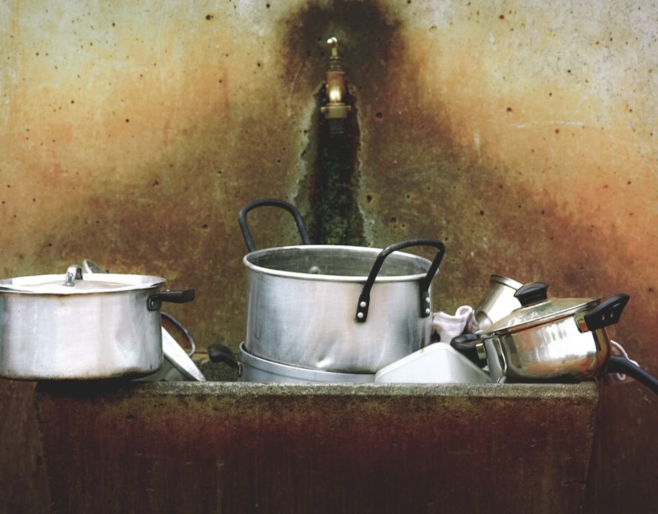 Qual o impacto de um cano entupido na rotina diária? kitchen utensils on stone washing station