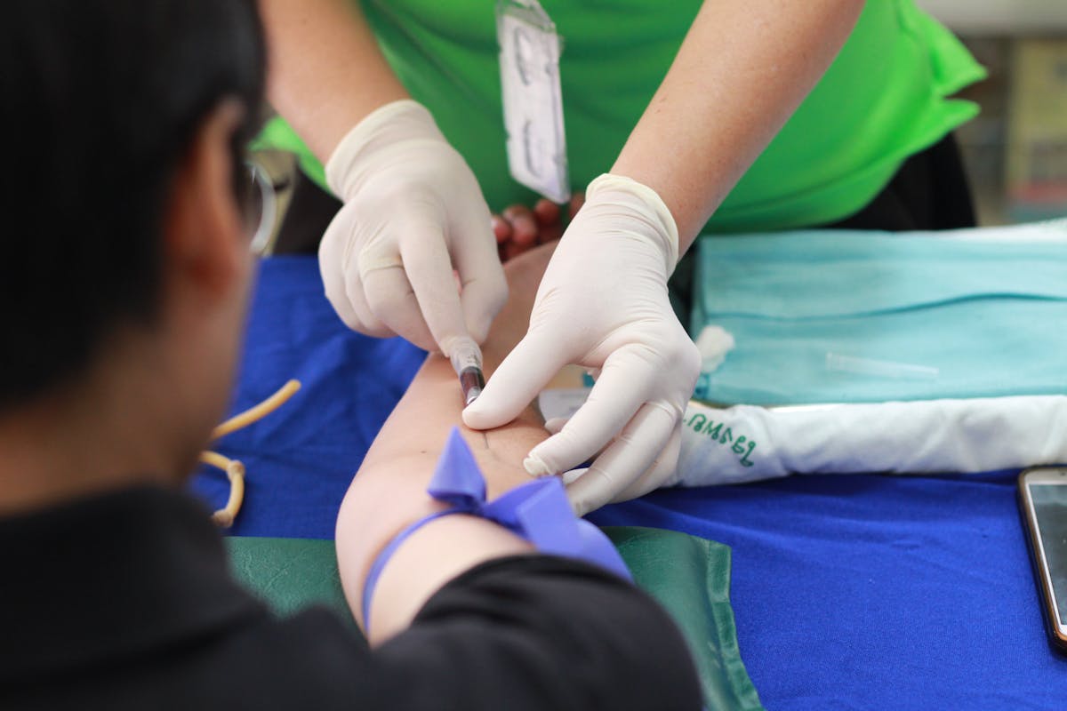 Quais profissões têm o futuro mais promissor no Brasil? A healthcare professional administering an injection to a patient's arm during a medical procedure.