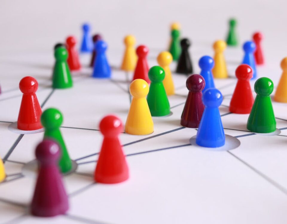 Como as redes sociais influenciam decisões na vida real A strategic arrangement of colorful pawns connected on a game board, symbolizing networking and teamwork.