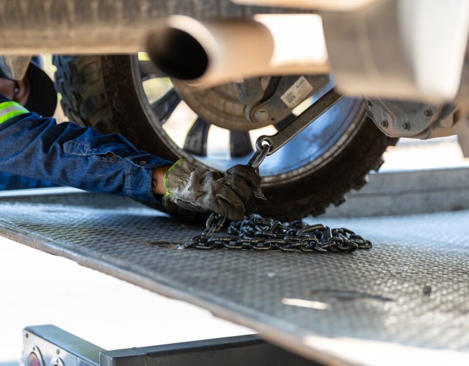 Como funcionam os serviços de guincho no Brasil? Mechanic securing a vehicle on a service platform with a chain for safe towing.