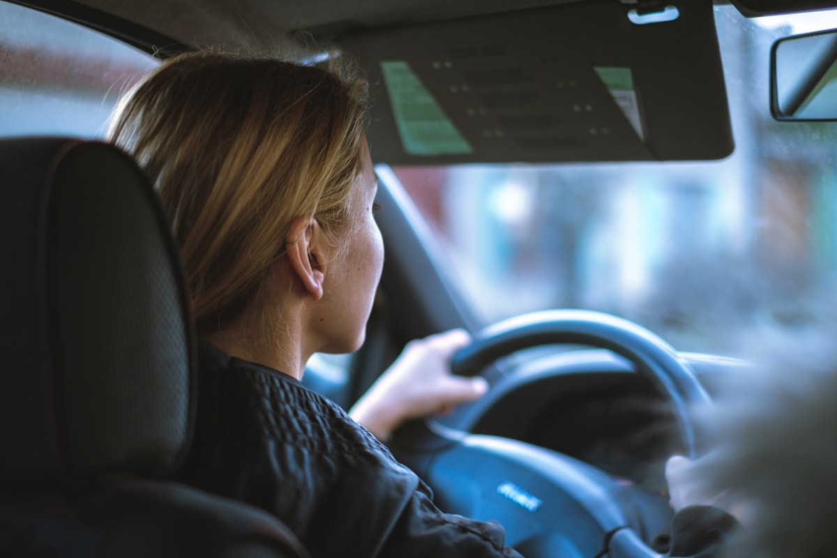 É possível ter CNH sem fazer autoescola? a woman sitting in a car with a steering wheel