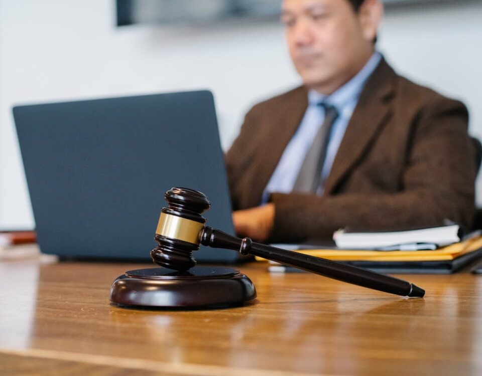 Como saber se o advogado é ideal para seu plano de saúde? Crop concentrated Asian male judge in formal clothes sitting using modern netbook while working in law office