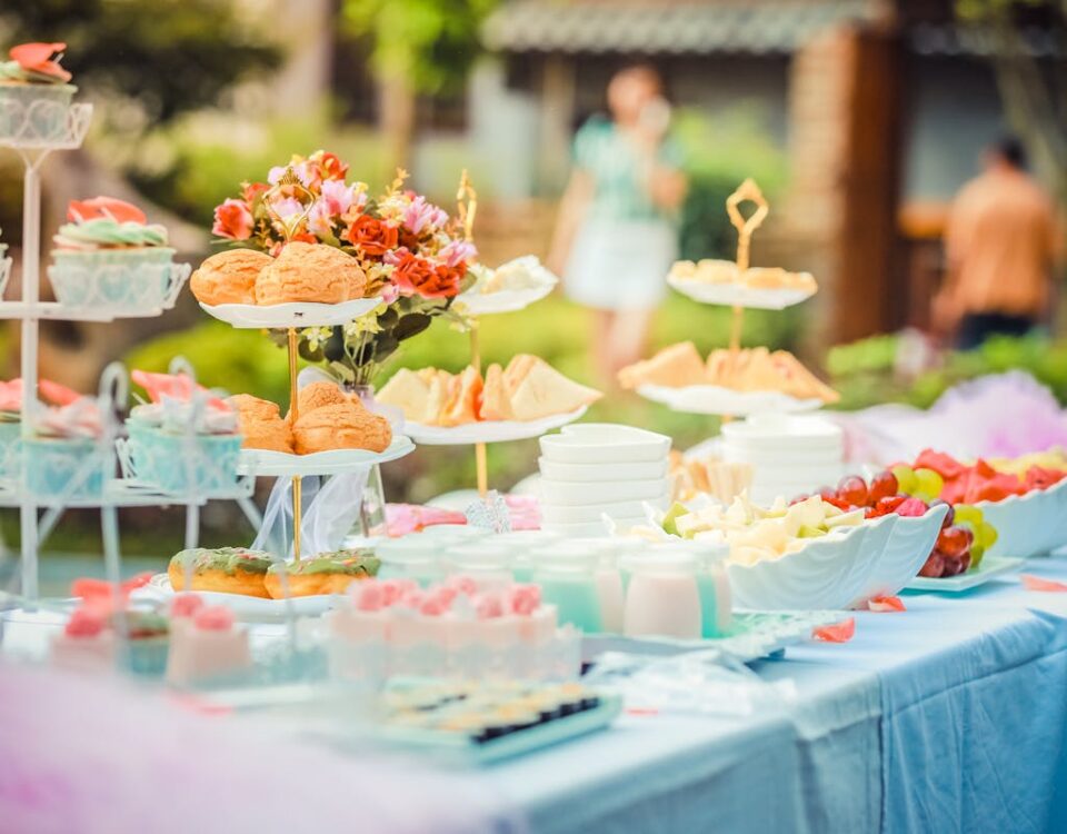 O que diferencia um buffet de qualidade em eventos? A vibrant outdoor buffet table showcasing an array of colorful pastries and fruits, perfect for parties.