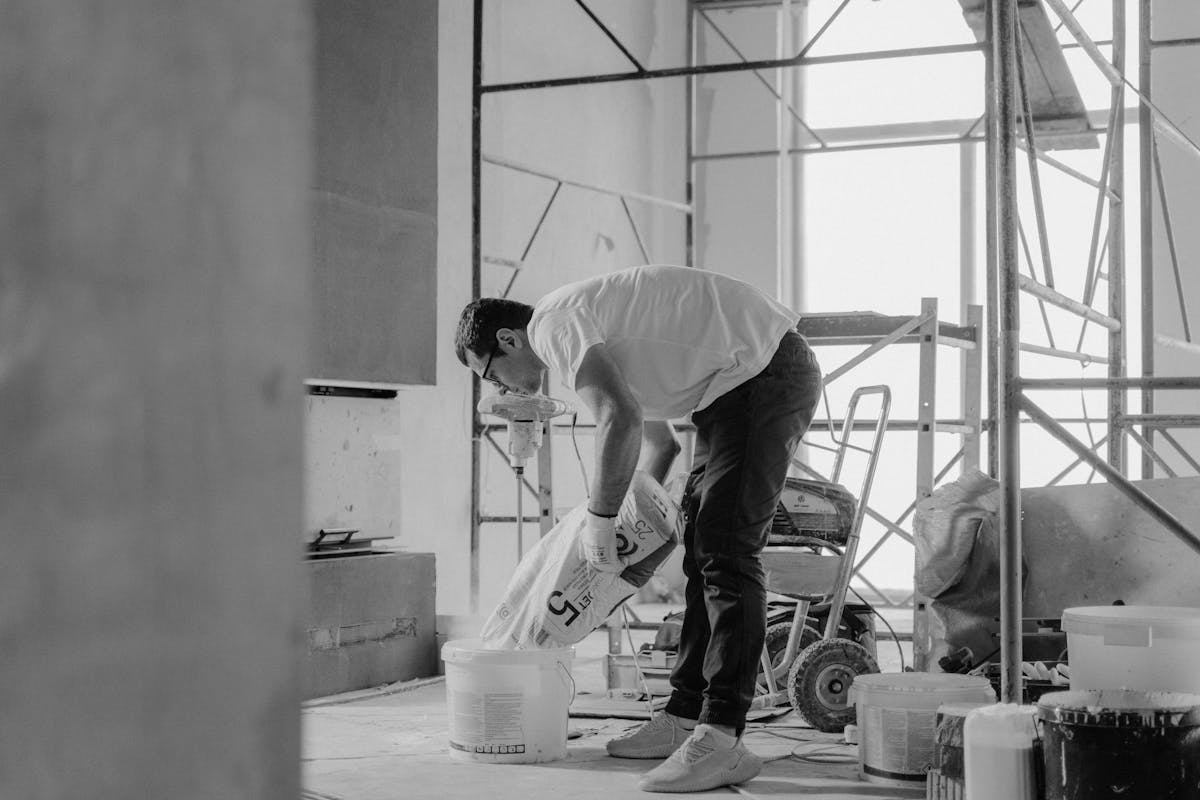 Como proteger sua casa contra infiltrações? A construction worker pours materials inside a building under renovation.