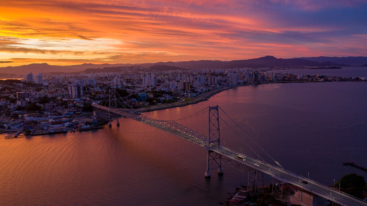 Qual é o segredo das cidades com melhor qualidade de vida? A stunning aerial view of Hercílio Luz Bridge during sunset in Florianópolis, Brazil.