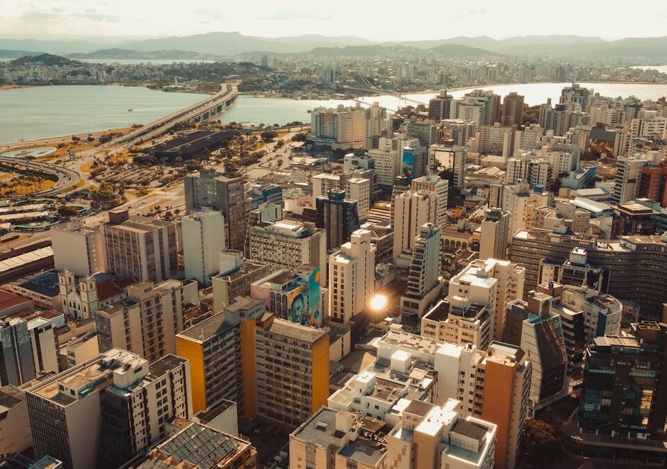 Qual é o segredo das cidades com melhor qualidade de vida? A breathtaking aerial view of Florianópolis featuring skyscrapers and the coastal skyline under a bright day.