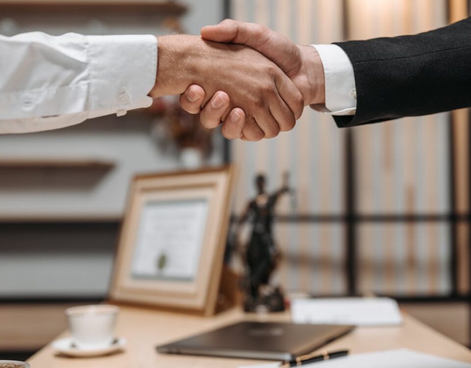 Como funciona a assistência jurídica gratuita no Brasil? Close-up of a handshake between two professionals in a modern office setting, emphasizing partnership and agreement.