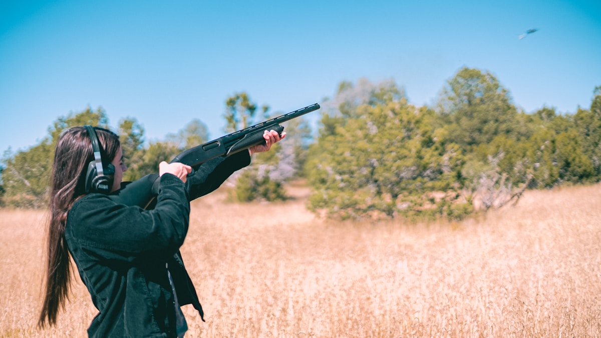 O que diferencia espingardas e carabinas? a woman holding a gun in a field