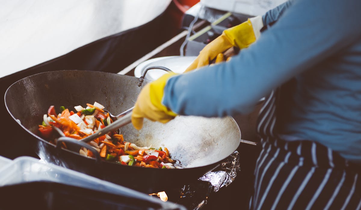 A chef stir-frying vegetables in a wok, showcasing vibrant fresh ingredients.