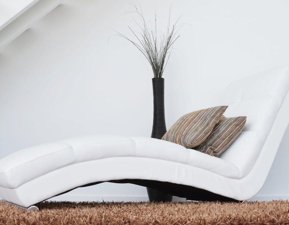 Qual móvel de luxo combina com sua personalidade? Elegant white lounge chair with cushions on plush carpet, perfect for relaxation.