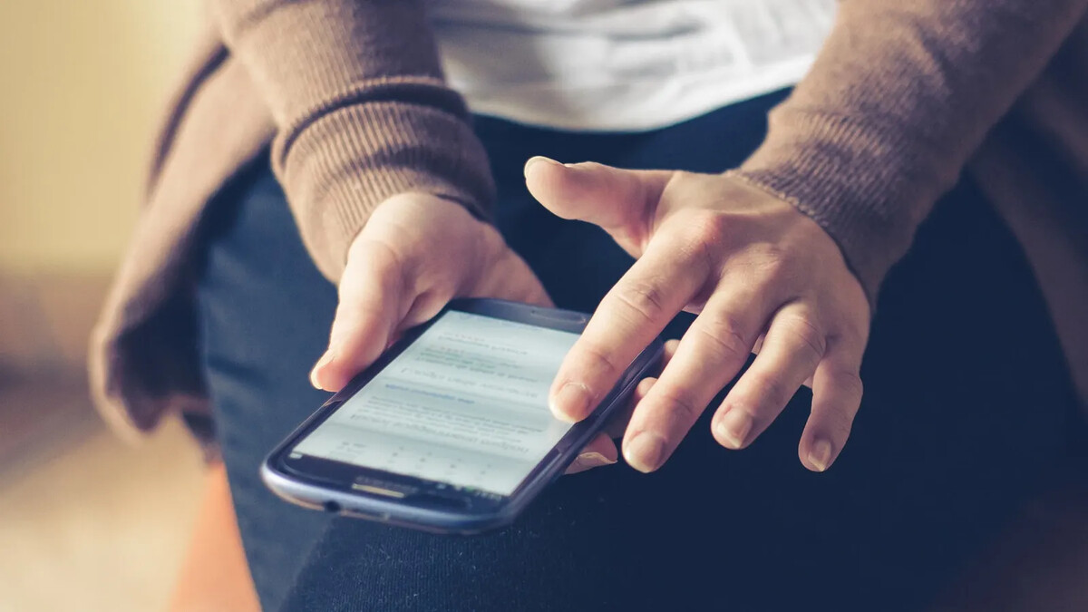 Adulto segurando smartphone com as duas mãos