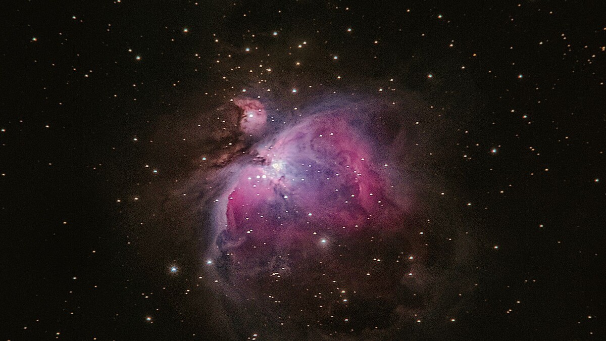 Nebulosa de Órion em cor rosada cercada de estrelas