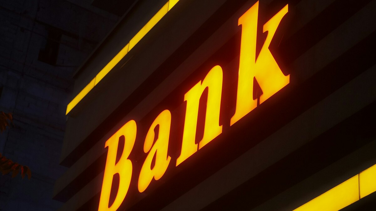 Consultor de crédito ou gerente do banco: quem acha juro menor? Placa iluminada de agência bancária à noite