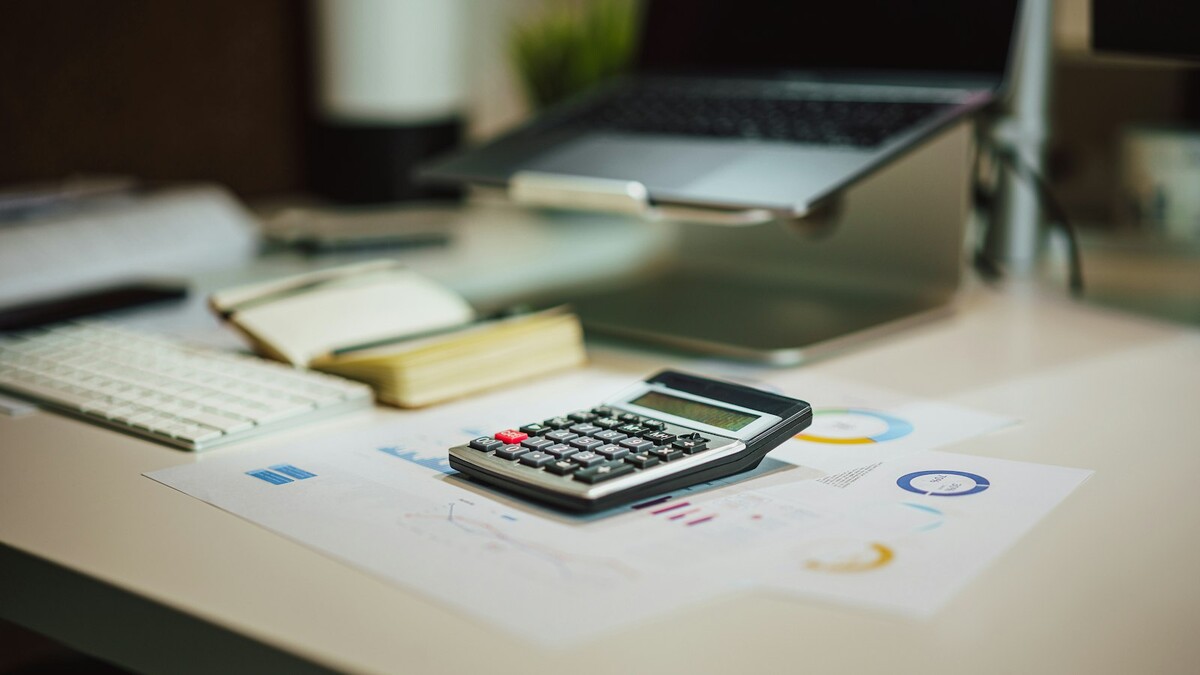 Consultor de crédito ou gerente do banco: quem acha juro menor? Calculadora sobre a mesa ao lado de um notebook