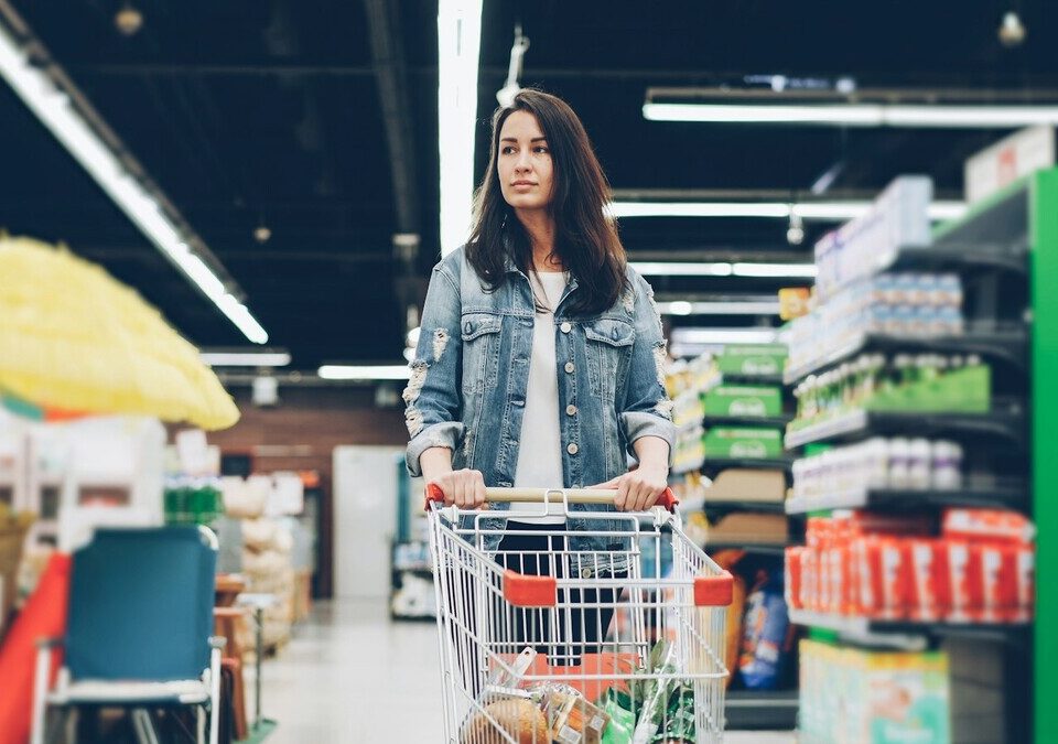 Mulher empurrando um carrinho em um corredor de supermercado