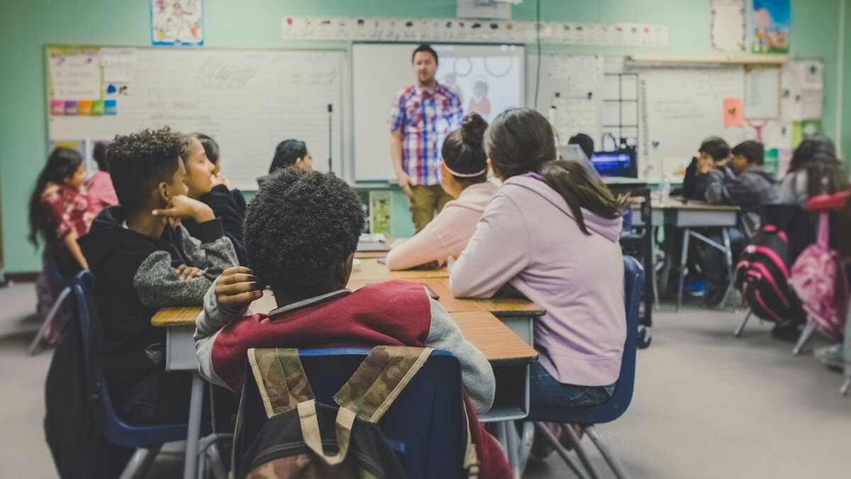 Professora apresentando conteúdo para alunos em uma sala de aula