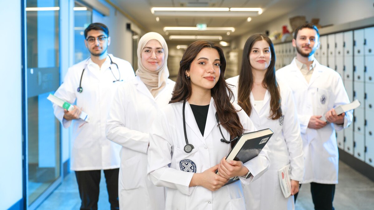 Enamed obrigatório aprovado: o que muda para quem estuda medicina Grupo de estudantes de medicina de jaleco em corredor de universidade
