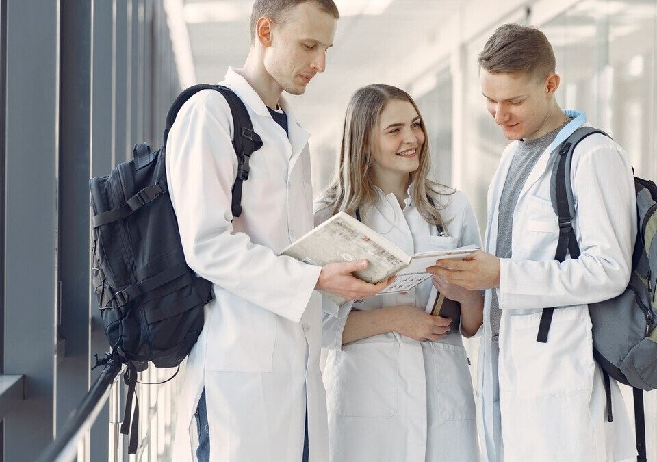 Estudantes de medicina de jaleco conversando em corredor de hospital
