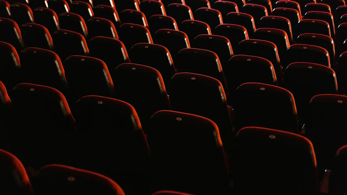 Festival de Cinema Francês 2026: datas, filmes e ingressos Sala de cinema vazia com fileiras de poltronas vermelhas