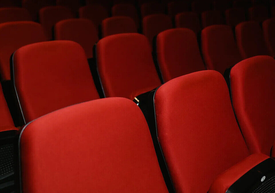 Fileiras de poltronas vermelhas em sala de cinema