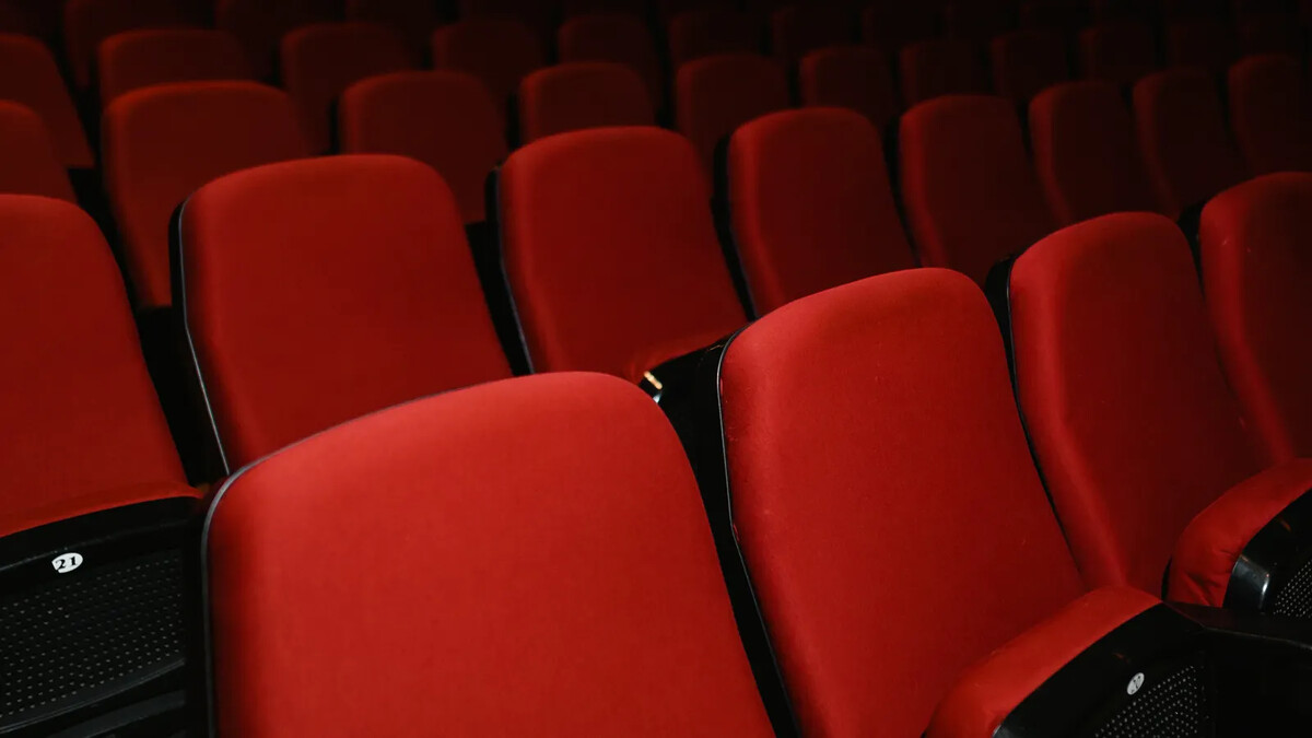 Fileiras de poltronas vermelhas em sala de cinema