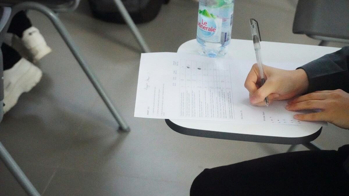 Pessoa escrevendo à mão em uma folha de papel sobre a mesa