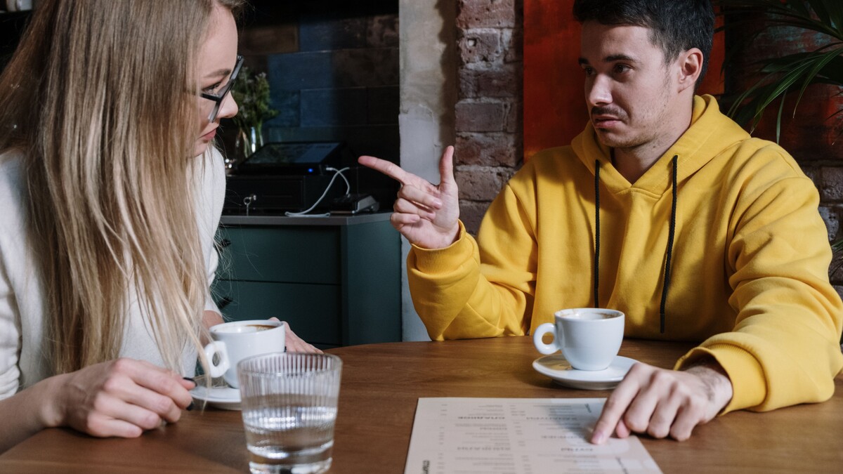 O que avaliar ao escolher entretenimento adulto em Curitiba? Duas pessoas adultas conversando à mesa de um café.