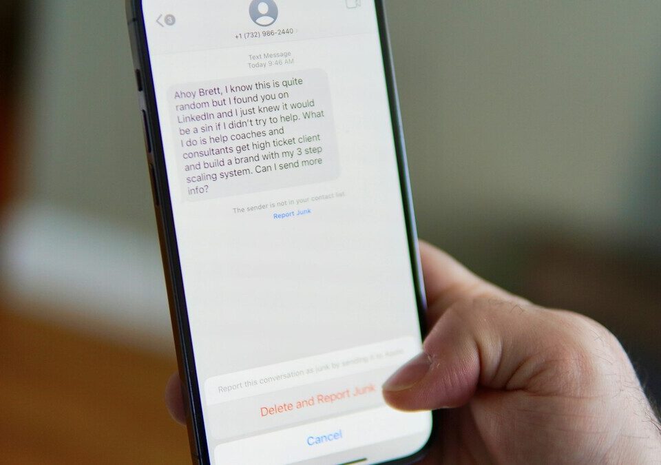 Mão segurando smartphone com uma conversa de mensagens aberta na tela