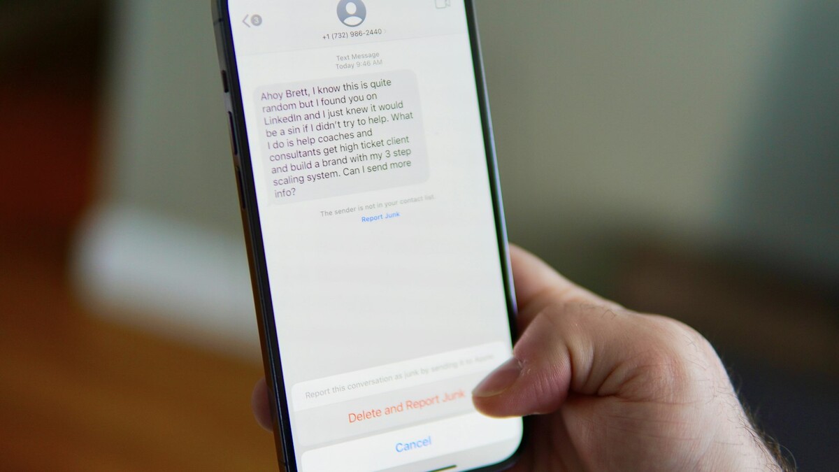 Mão segurando smartphone com uma conversa de mensagens aberta na tela